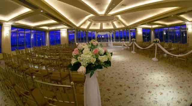 Elegant wedding ceremony at Glen Island Harbour Club with floral arrangements and gold chairs.