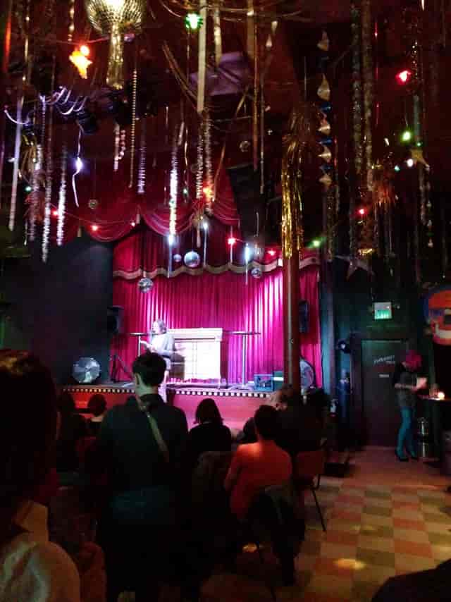 Vibrant event space at The Make Out Room with red curtains, ideal for performances and gatherings.