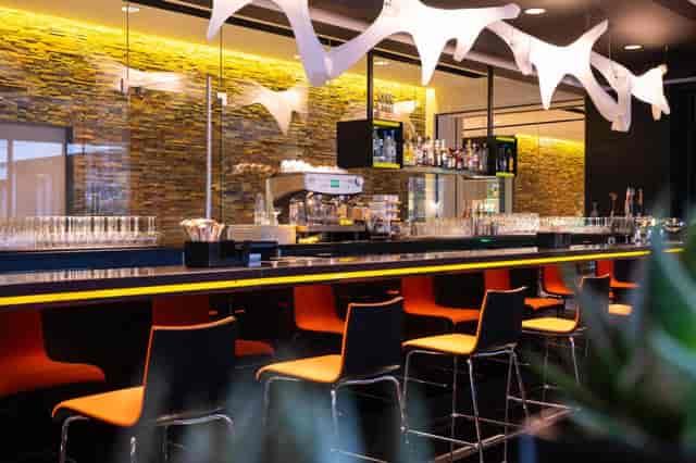 Modern bar at Novotel Amsterdam City with vibrant seating, perfect for events.