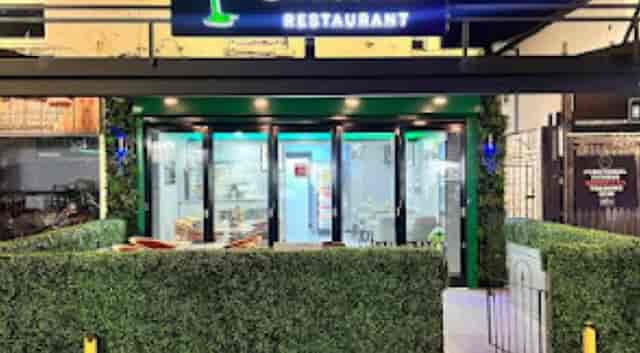 Modern Nande Caribbean Restaurant entrance with greenery, perfect for events and gatherings.