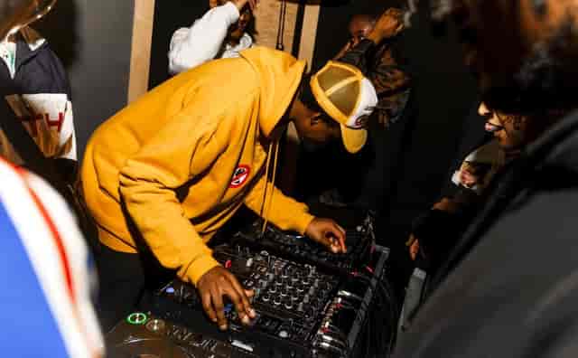 DJ booth at ALL IS JOY event, creating an energetic atmosphere with vibrant music.
