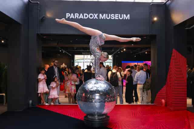 Acrobat on disco ball at Paradox Museum London event space, vibrant entertainment experience.