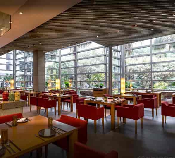 Modern dining space at Four Seasons Hotel Mumbai with vibrant red chairs and natural light.