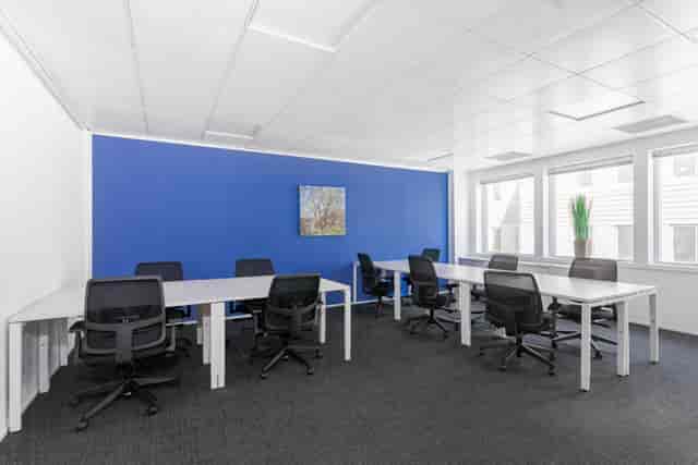 Modern meeting room with blue accent wall, ideal for workshops and team discussions.