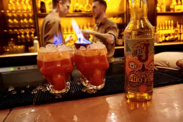 Vibrant cocktail bar in Aluna Birmingham with flaming drinks in skull glasses.