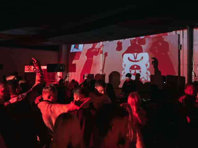 Vibrant warehouse event with attendees dancing to live music and dynamic lighting.