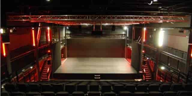 Versatile event space with modern stage and tiered seating for performances and conferences.