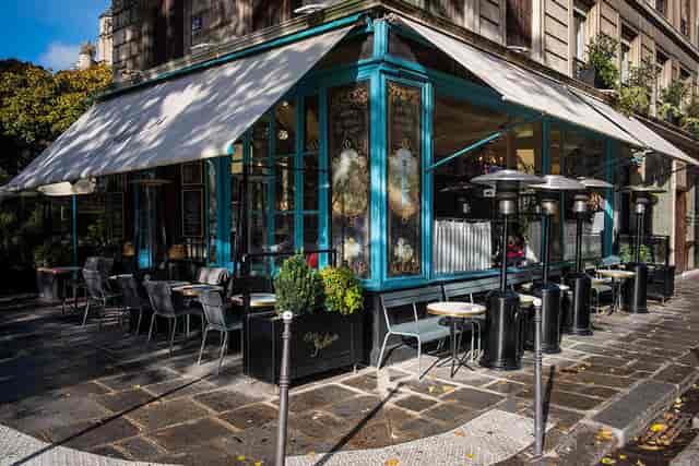 Charming outdoor café at Chez Julien with vibrant blue façade, ideal for networking events.