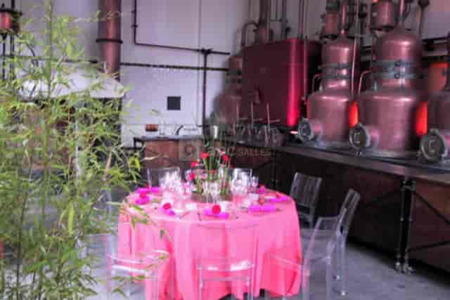 Stylish event setup with pink linens and acrylic chairs in industrial distillery space.