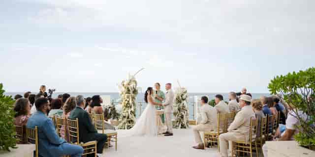 Outdoor wedding ceremony at Condado Vanderbilt Hotel with ocean backdrop and floral arrangements.