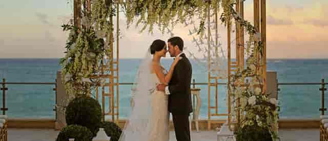 Elegant wedding ceremony in Salón Dorado, Condado Vanderbilt Hotel with floral arch.