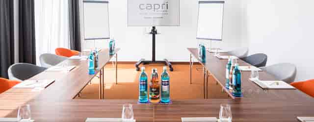 Meeting room setup for professional event with U-shaped tables and natural light.
