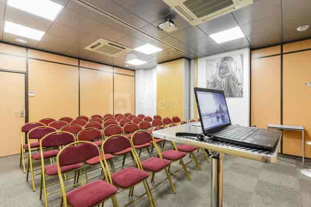 Meeting room with red chairs and podium, perfect for presentations and workshops.