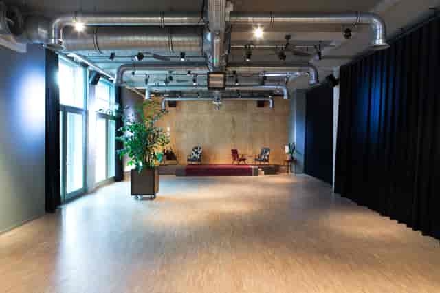 Versatile event space in Volkshotel with natural light, ideal for meetings and gatherings.