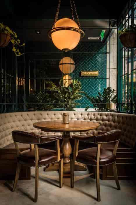 Cozy round table in stylish bar at The Optimist, ideal for meetings and networking events.