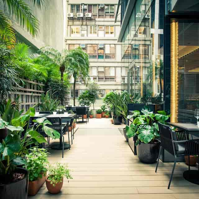 Vibrant outdoor event space with lush greenery and modern furniture for meetings.