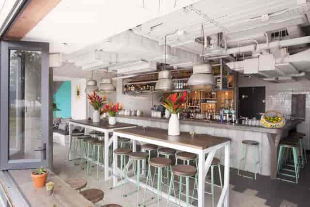 Modern bar area in Limewood, featuring a communal table for networking events.