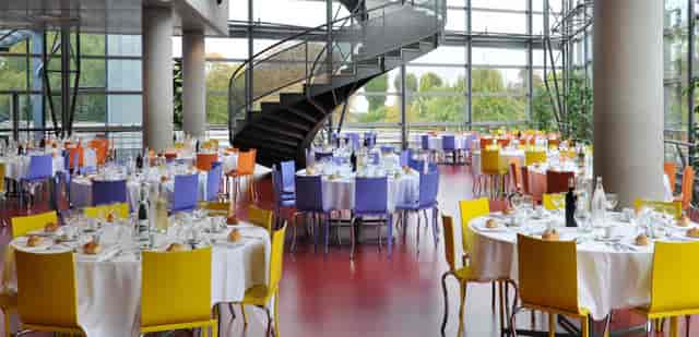 Elegant event space with round tables and spiral staircase in Reims Congress.