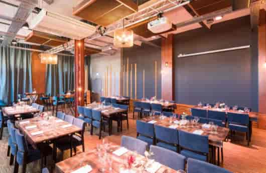 Elegant event space with wooden tables and blue chairs in Palais Kultubrauerei.