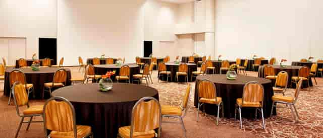 Spacious Sheraton Milan Malpensa event venue with round tables for meetings and banquets.