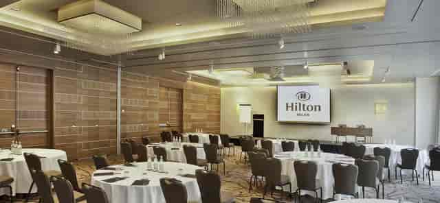 Ballroom at Hilton Milan with round tables for corporate events and conferences.