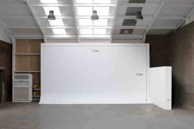 Spacious minimalist event space with white backdrop for corporate meetings and artistic events.