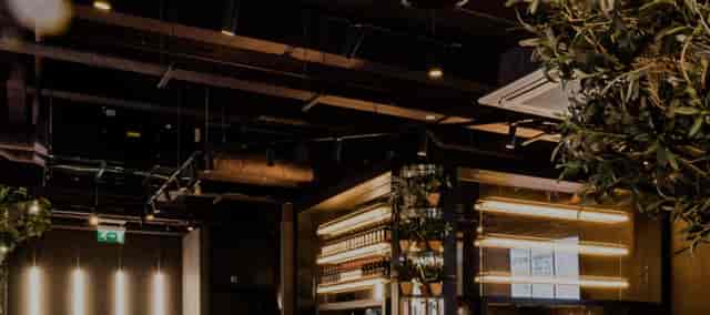 Modern industrial venue in PizzaLuxe Manchester for events, featuring warm lighting and greenery.