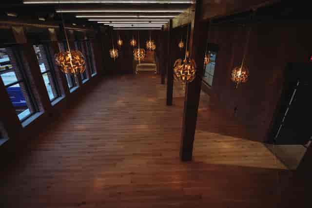 Spacious event venue with wooden flooring and pendant lights, ideal for meetings and gatherings.