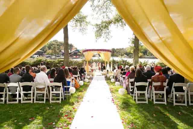 Outdoor wedding ceremony at Riverside Lawn, Boston Marriott Newton with yellow drapery.