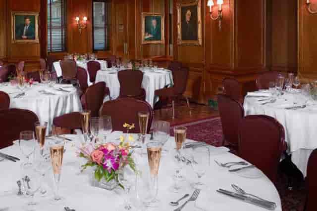 Elegant bar and grill dining setup with white linens for corporate events and gala dinners.