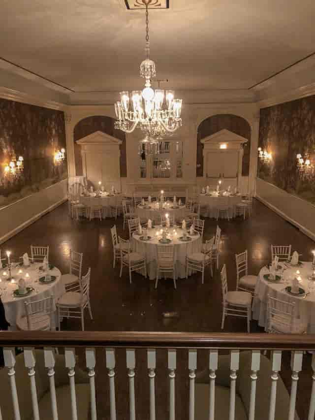 Elegant event space at Clubhouse, featuring round tables with white linens and green accents.