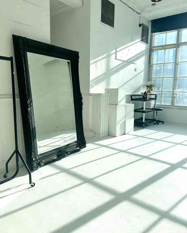 Bright minimalist event space with large mirror, perfect for gatherings and workshops.