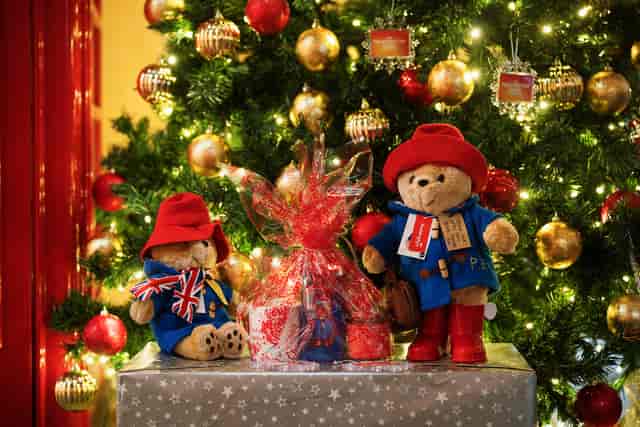 Teddy bears in holiday attire at The Paddington Bear Experience Christmas party setup.