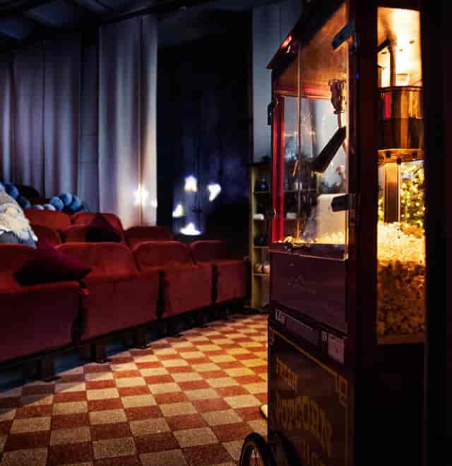 Cozy vintage cinema with plush red seating and popcorn machine for intimate screenings.