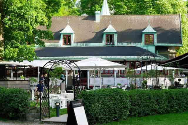 Charming outdoor venue at Villa Godthem with rustic building and lush greenery.