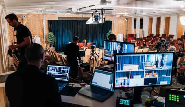 Hybrid event setup in IVA Conference Centre with cameras and screens for live streaming.