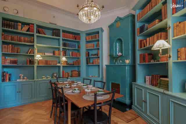Cozy meeting space at La Bibliothèque, featuring turquoise bookshelves and elegant chandelier.