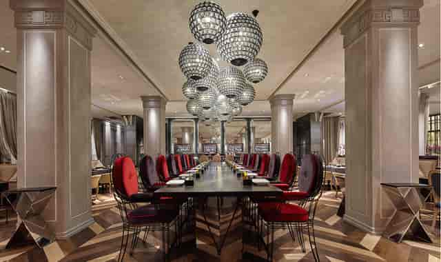 Elegant dining area with long table, plush red chairs for corporate events.