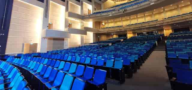 Sands Theatre auditorium with tiered seating and vibrant blue chairs for events.