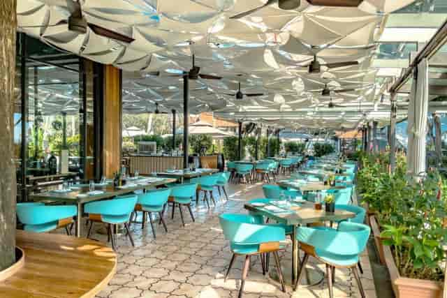 Vibrant dining space with turquoise chairs at Club Matera, ideal for events in Singapore.