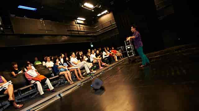 Speaker engaging audience in theater at Black Box, Arts House Limited for impactful events.