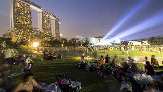 Vibrant outdoor event at The Meadow, illuminated backdrop, community gathering.