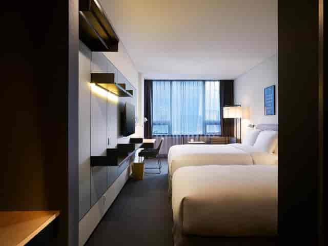 Modern hotel room with twin beds, ideal for business events and comfort.