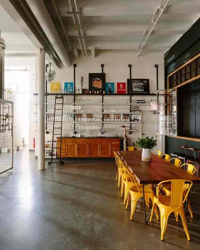 Modern tasting room with wooden table and yellow chairs, ideal for workshops and networking.