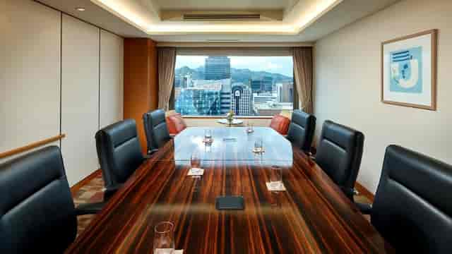 Modern conference room with wooden table and city view for corporate events.