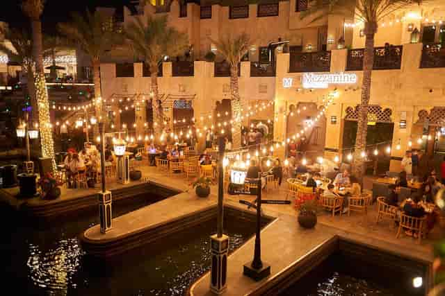 Outdoor dining area at Mezzanine, illuminated by string lights for events.