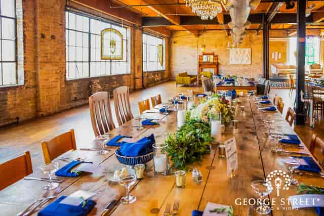 Elegant event space with wooden table, blue napkins for corporate meetings and social events.
