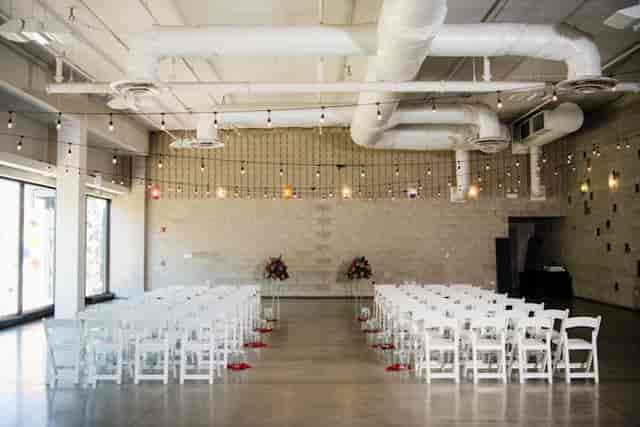 Spacious event venue with white chairs, ideal for weddings and corporate events.