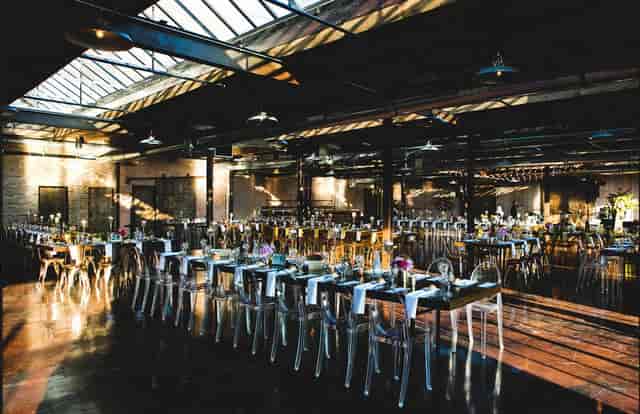Spacious industrial-chic event venue with elegant long tables for gatherings.
