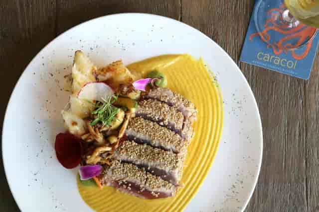 Seared meat dish with vibrant sauces at Conchita, Caracol event catering.